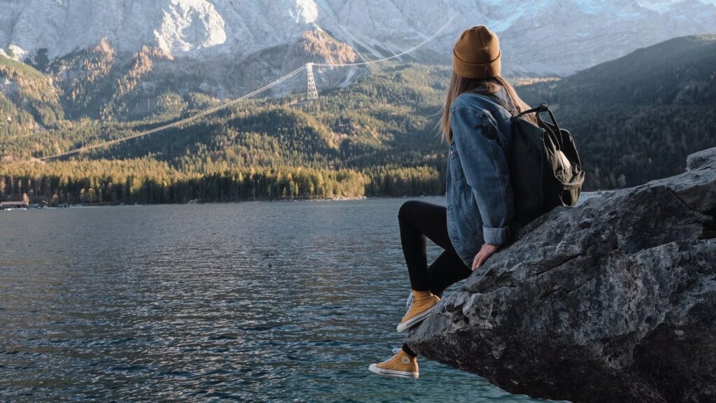 a person sitting on a rock looking at the mountains